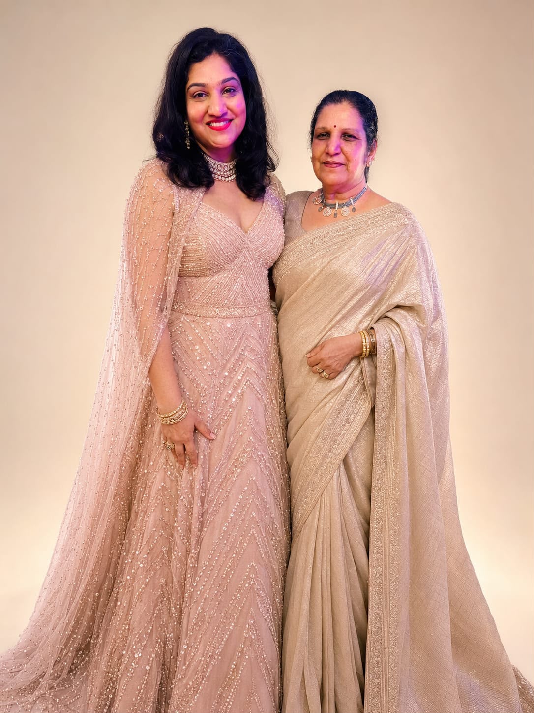 Bhargavi standing with her mother in matching blush celebration outfits